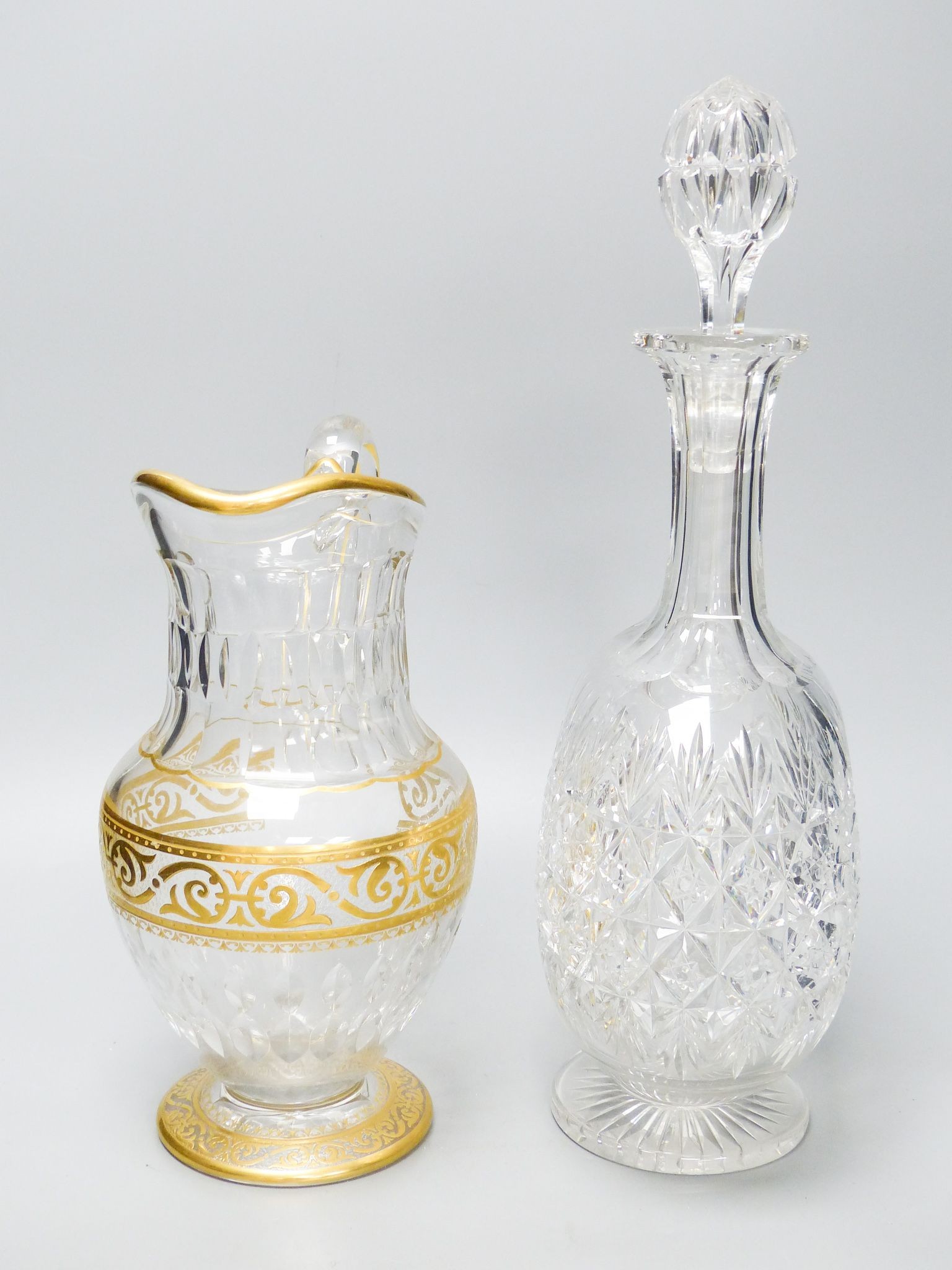 A Baccarat gilt and cut glass jug and a strawberry cut glass decanter and stopper, tallest 38 cm